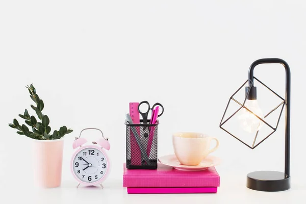 Despertador rosa con cuaderno sobre fondo blanco —  Fotos de Stock