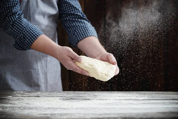 Mãos cozinhando massa no fundo de madeira escura — Fotografia de Stock