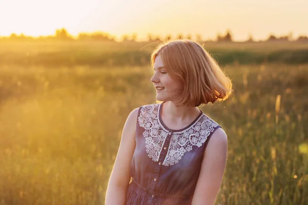 Tonåring flicka i sommar fältet vid solnedgången — Stockfoto