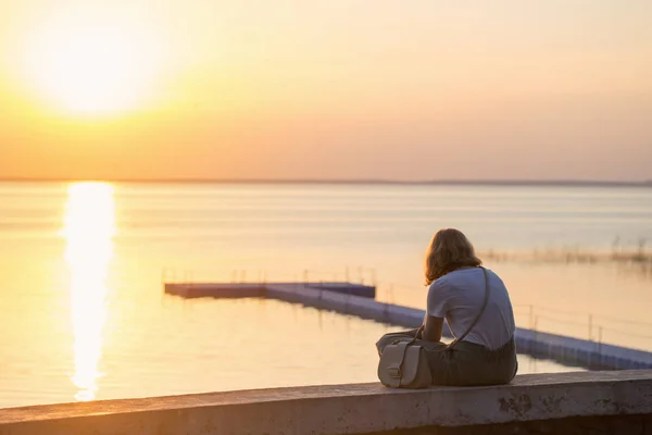 Girl sitting on the promenade at sunset — Stock Photo, Image
