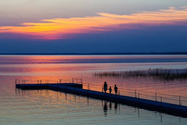 Family on pontoon pier at sunset — Stock Photo, Image