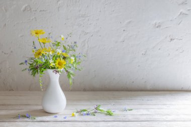 wildflowers in white vase on background old wall clipart