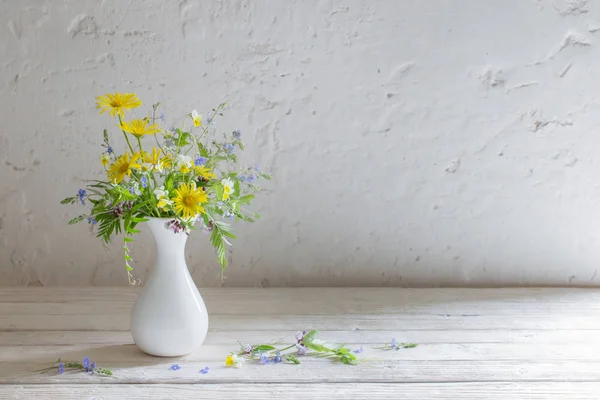 Flores silvestres en jarrón blanco sobre fondo pared vieja —  Fotos de Stock