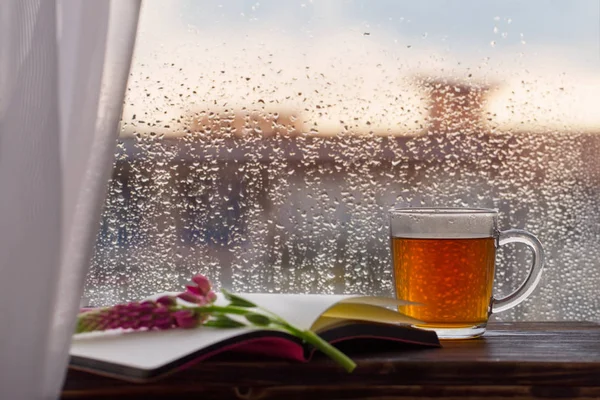 Taza de té en el fondo de la ventana con gotas de lluvia al atardecer — Foto de Stock
