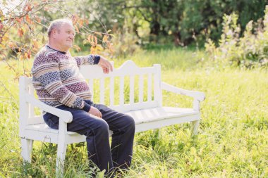 sonbahar Park beyaz bankta oturan yaşlı adam