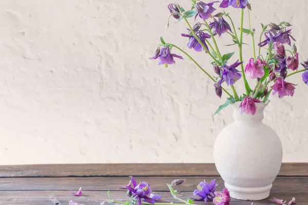 Flores aquilegia en jarrón blanco sobre mesa de madera —  Fotos de Stock