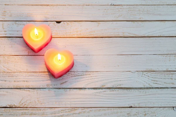 Růžové hořící svíčky na bílém dřevěném pozadí — Stock fotografie