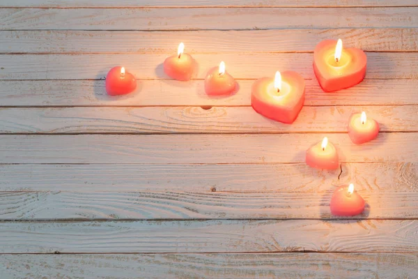 Růžové hořící svíčky na bílém dřevěném pozadí — Stock fotografie