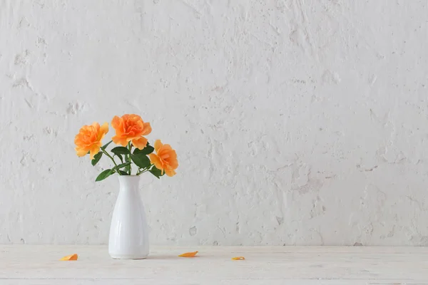 Róże w wazonie na tle białej ścianie — Zdjęcie stockowe