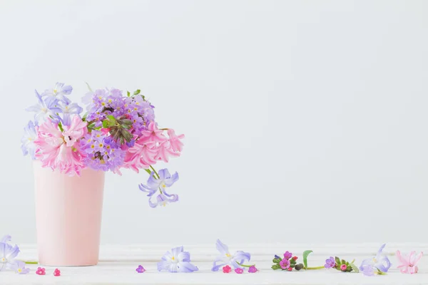 Blauwe en roze bloemen in vaas op witte tafel — Stockfoto
