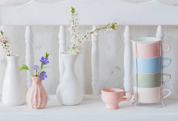 Чашки и вазы с весенними цветами на винтажной деревянной белой полке — стоковое фото