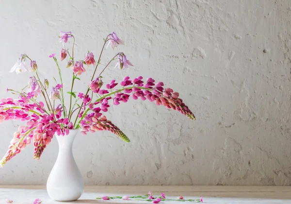 Fleurs d'été roses dans un vase blanc sur fond blanc ancien — Photo