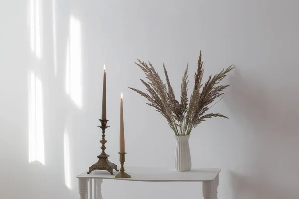 Ramo de flores silvestres y velas ardientes a la luz del sol en blanco i — Foto de Stock