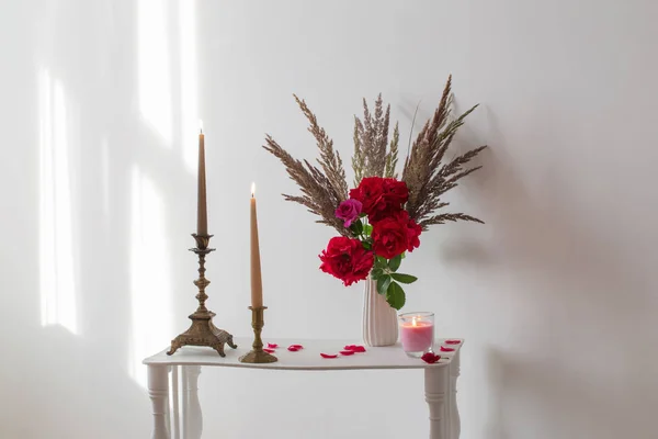 Interior blanco con ramo de rosas y velas encendidas —  Fotos de Stock