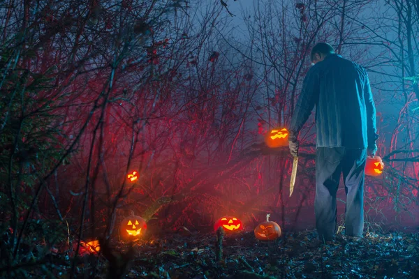 Gece ormanında korkunç adam Halloween kabak kesiyor — Stok fotoğraf