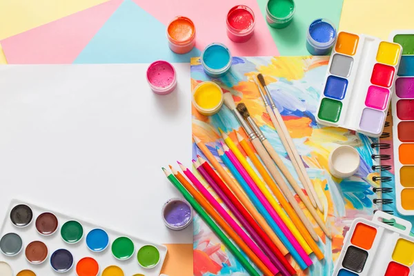 Краски, карандаши и кисти на бумаге — стоковое фото