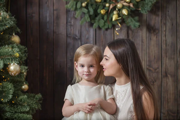 Mutter und Tochter am Weihnachtsbaum auf hölzernem Hintergrund — Stockfoto