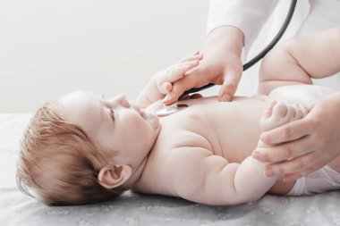 Doktor için küçük çocuk stetoskop ile dinler.