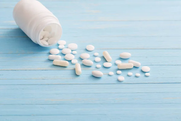 White pills on  blue wooden background — Stock Photo, Image