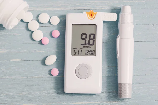 Gri ahşap arka plan üzerinde glucometer ve haplar — Stok fotoğraf