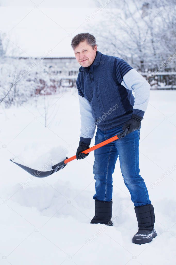 man cleans snow shovel