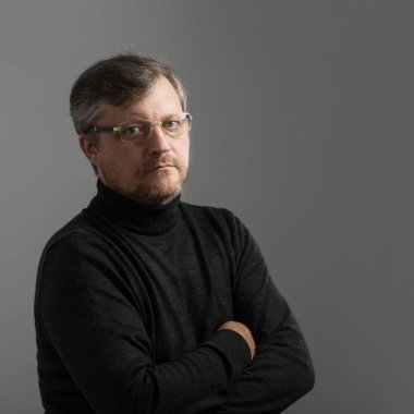 Gri arka planda sakallı olgun bir adam.