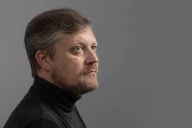 Gri arka planda sakallı olgun bir adam.