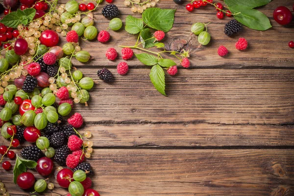 Different berries on old wooden background — Stock Photo, Image