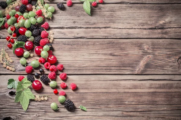 Different berries on old wooden background — Stock Photo, Image