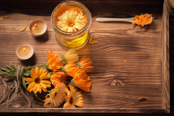 Medicinal flowers of calendula with burning candles  on dark woo — Stock Photo, Image