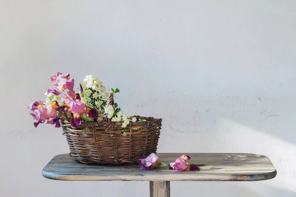 Iris en cesta sobre mesa de madera sobre fondo de w viejo — Foto de Stock