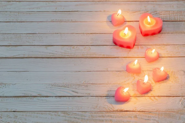 Rosa queimando velas no fundo de madeira branco — Fotografia de Stock
