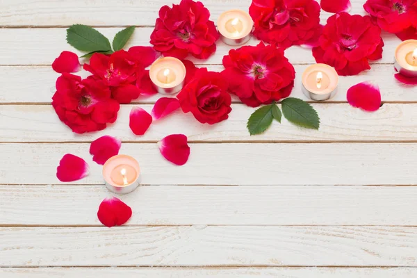 Roses rouges et bougies allumées sur fond blanc en bois — Photo