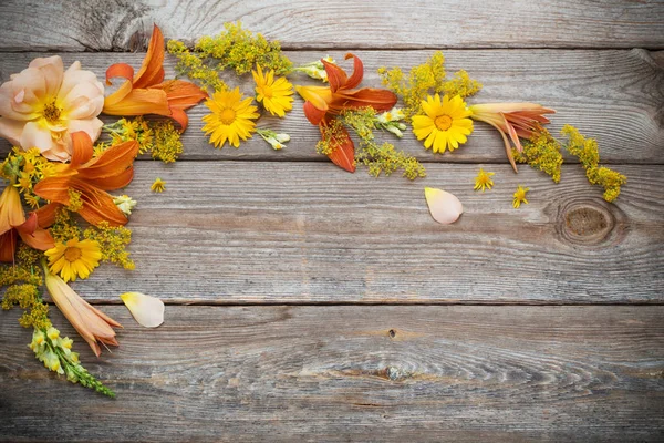Žluté a oranžové květy na starém dřevěném pozadí — Stock fotografie