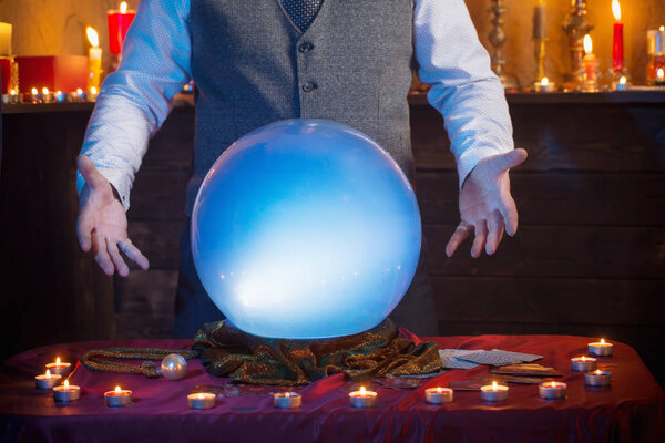 Hands of fortune teller with illuminated crystal ball