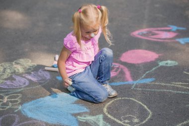 Küçük kız kaldırımda tebeşirle çiziyor