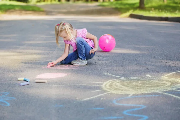 A kislány krétát rajzol a járdára. — Stock Fotó