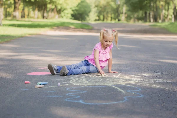 Niña dibuja con tiza en el pavimento — Foto de Stock