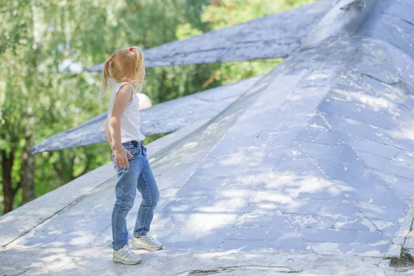 Malá holčička hraje v parku na staré kovové ploše — Stock fotografie
