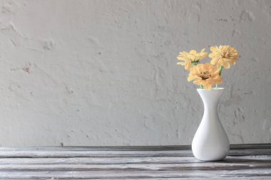 ahşap masa üzerinde beyaz vazo sarı zinnia 