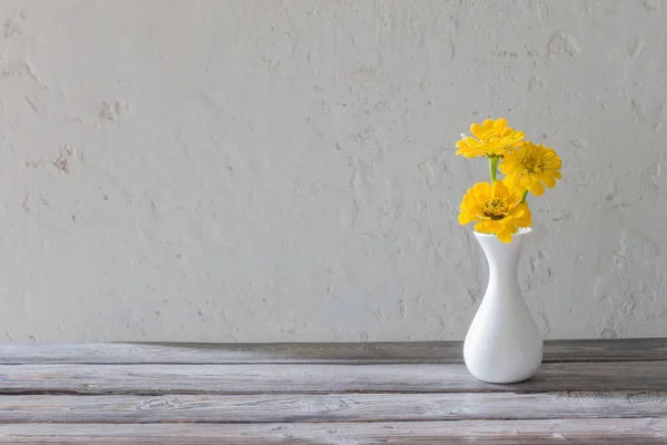 Zinnia amarilla en jarrón blanco sobre mesa de madera — Foto de Stock