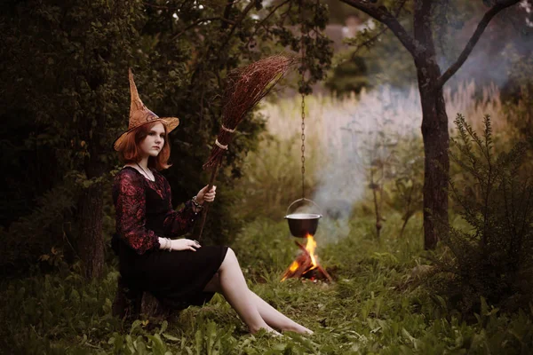 Bruja joven por el fuego en el bosque nocturno — Foto de Stock