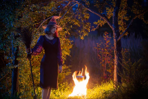 Bruja joven por el fuego en el bosque nocturno — Foto de Stock