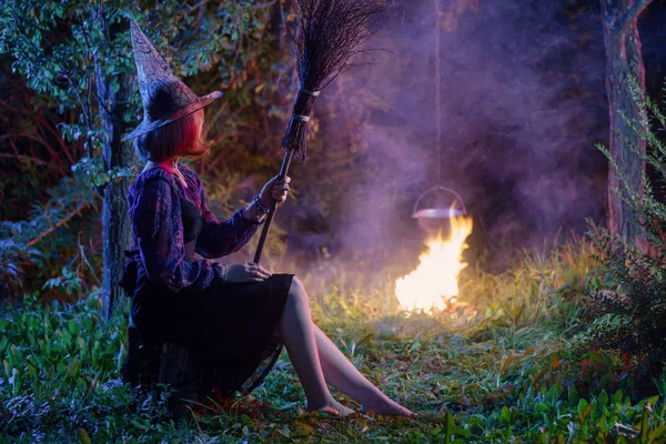 Jovem bruxa pelo fogo na floresta noturna — Fotografia de Stock