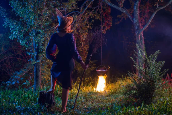 Jovem bruxa pelo fogo na floresta noturna — Fotografia de Stock