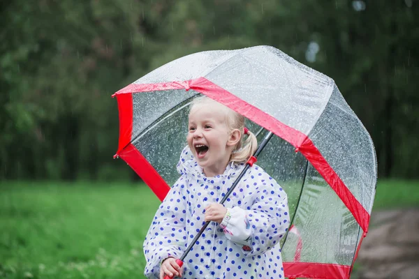 Смешная маленькая девочка с зонтиком под дождем — стоковое фото