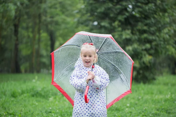 Смешная маленькая девочка с зонтиком под дождем — стоковое фото