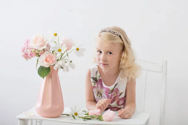 白い背景に花を持つ美しい小さなブロンドの女の子 — ストック写真