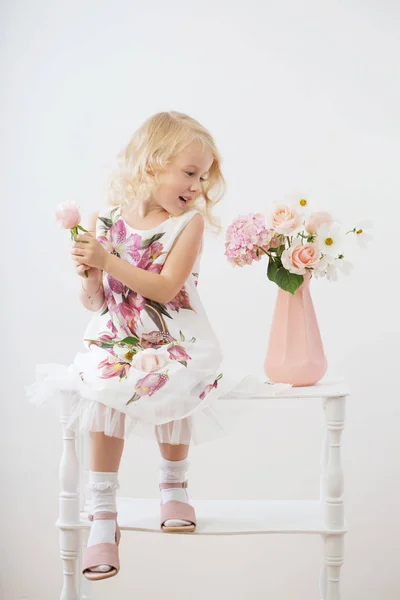 Beautiful little blonde girls with  flowers on white background — Stock Photo, Image