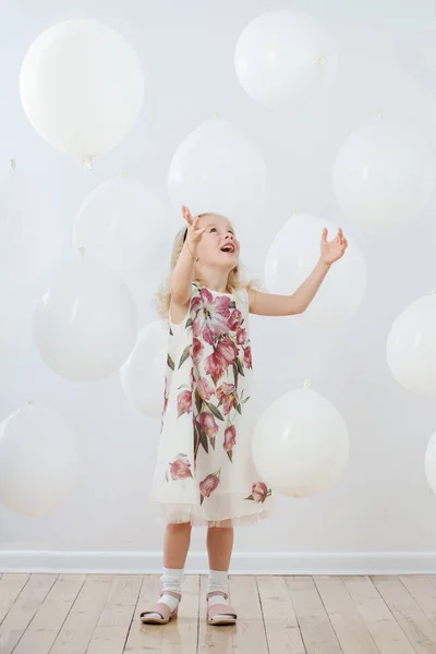 Kleines Mädchen mit weißen Luftballons drinnen — Stockfoto